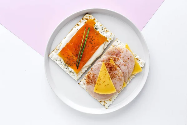 Salty crackers with salmon and cheese from above on colors background. Flat lay. Top view