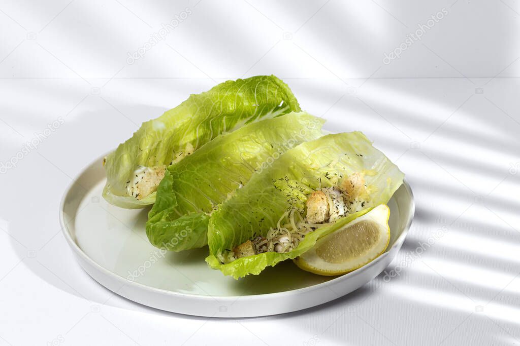Homemade Caesar salad with chicken, lettuce, lemon, toast, caesar sauce, cheese and garlic.On white background.Healthy food concept