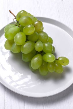 Taze mevsimlik üzümler tabakta, beyaz arka planda yenmeye hazır. Sağlıklı yiyecekler. Vejetaryen gıda konsepti