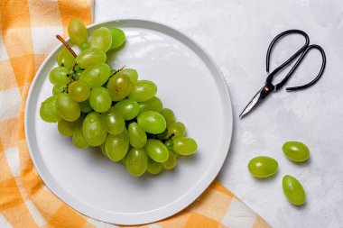 Taze mevsimlik üzümler tabakta, beyaz arka planda yenmeye hazır. Sağlıklı yiyecekler. Vejetaryen gıda konsepti