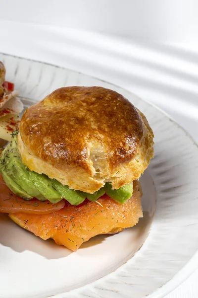 Assortment of homemade scones with ham, cheese, avocado, salmon, cream cheese and strawberry jam. Traditional english food