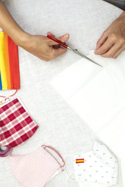 Tanımlanamayan bir kadının elleri kovid19 salgınından korunmak için maske takıyor. Coronavirus Ev Yapımı. makas