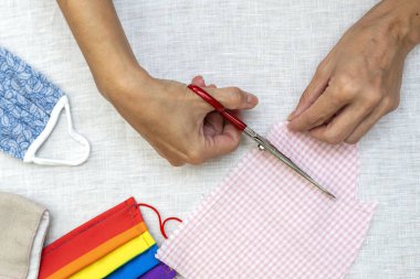 Tanımlanamayan bir kadının elleri kovid19 salgınından korunmak için maske takıyor. Coronavirus Ev Yapımı. makas