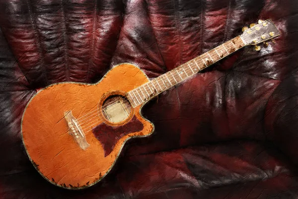 Aciustic country and western style guitar set onto a leather background