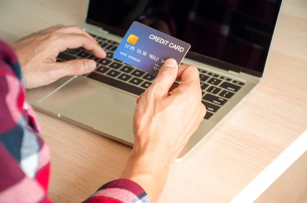 Online payment concept, The hands of young men using credit cards and using computers for online shopping or online bill payments.