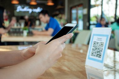 Kadınların elleri yemek menüsünü seçmek için QR kodunu tarıyor. İndirim için tarama yap ya da yiyecek için ödeme yap. Para transferi için telefon kullanma ya da nakit olmadan internet üzerinden para ödeme kavramı..