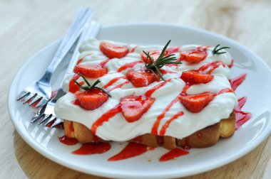 Yaz tatlısı. Krem şantili ekmek ve beyaz bir tabakta çilek.