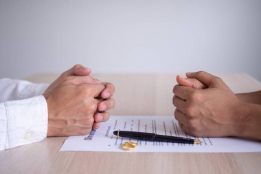 Karı ve kocanın elleri boşanma belgelerine bağlı. Boşanma belgeleri ya da bir avukatın hazırladığı evlilik öncesi anlaşmalar. Alyans sevgililerin anlaşmasını temsil eder..