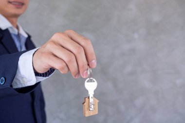 Takım elbiseli bir iş adamının ya da ev sahibinin ev temsilcisi müşterilere ev anahtarı gönderirken yakın plan çekimleri. Kirala ve fikir satın al.