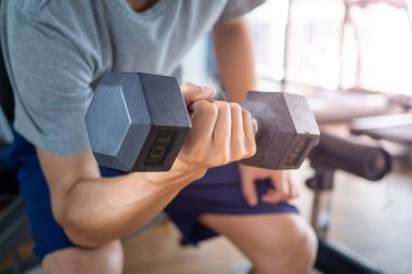 Spor salonunda, dambıl adamın kol egzersizinin yakın çekimi. Sağlık bakımı kavramı