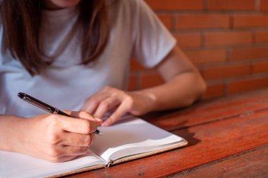 Bayan yazar ya da öğrenci dışarıda masanın üzerinde beyaz bir gömlek giyiyor. Parıldayan güzel ışıkla.