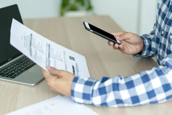 Adamın eli barkod ya da hesap dökümanlı qrcode 'u taramak için cep telefonu kullanıyor. Erkekler kredi kartı için banka başvurusu yaparlar. Konseptler çevrimiçi ürünler alır ve telefon teknolojisi kullanır.