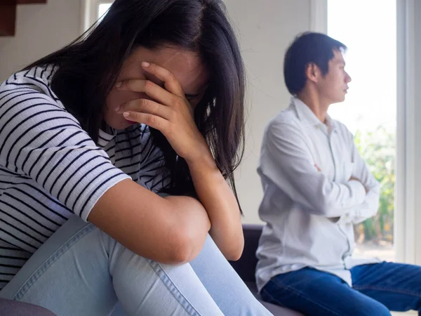 An Asian woman was crying on the couch inside the house after an argument with her husband. Concepts for sad couples with family problems or issues, divorce or quarrels