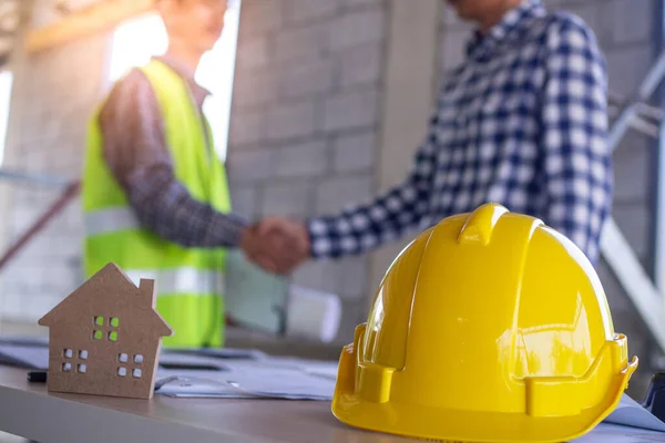 Müteahhit ve mühendis ev ya da bina inşa etmek için el sıkışıyor. İnşaat işçisi iş ücretlerini kabul eder. İnşaat alanlarının denetimi ve inşaat veya onarım maliyetleri