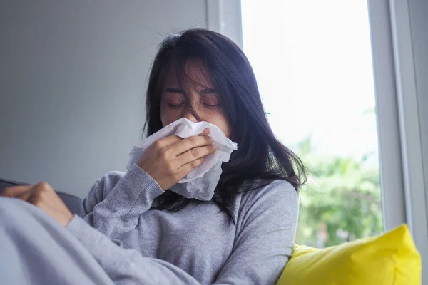 病気の女の子は 鼻水熱を持ち 病気のハンカチで拭く 家の中のソファに座っています 冷たい くしゃみをする — ストック写真