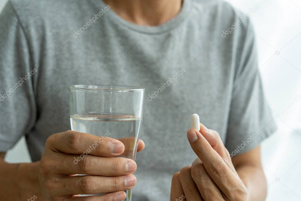 hand's man holding a dietary supplement or medication or vitamin and a glass of water ready to take. healthcare, medicine,Self-care,Illness and pharmacy concept.
