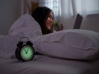 Asyalı bir kadın, gece yatmadan önce erkek arkadaşıyla telefonda video görüşmesi yapmak için akıllı telefon kullanıyor. Akıllı telefon bağımlılığı