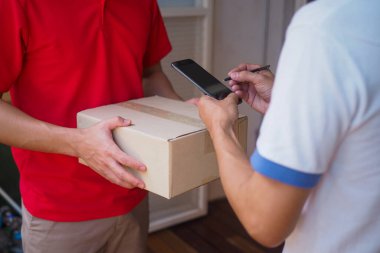 Çevrimiçi siparişçiler teslimatçı 'dan gelen paketleri onaylamak için akıllı telefonlarını imzalamak üzereler..