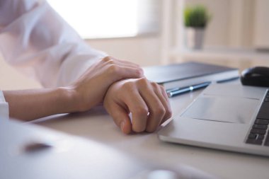 İş kadınının uzun zamandır bilgisayar kullanmaktan bileğinde ağrı var. Ofis sendromu