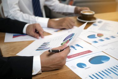 Çalışanlar şirketin performansının ilerlemesini yöneticilere sunuyorlar. Açıklama için grafik ve istatistiksel veri olarak belgeler var.