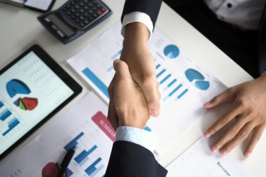 Toplantıdan sonra iş birliği yapmayı kabul ettim. Başarılı iş adamları tokalaşıyor.