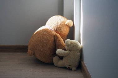Çocuk hüznü konsepti. Oyuncak ayı evin duvarına yaslanmış, üzgün ve hayal kırıklığına uğramış görünüyor..