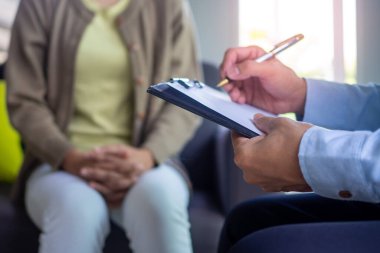 Psikiyatrist hastanın zihinsel semptomlarını kaydediyor. Önerinin yanı sıra danışmanlık ve danışmanlık da yap.