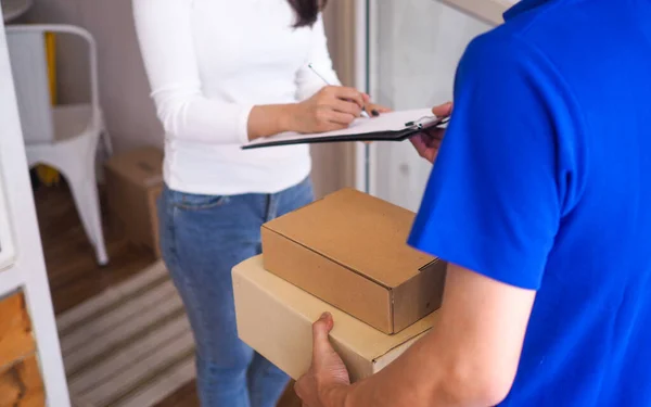 The woman is signing the name of the delivery staff sent to the front door.