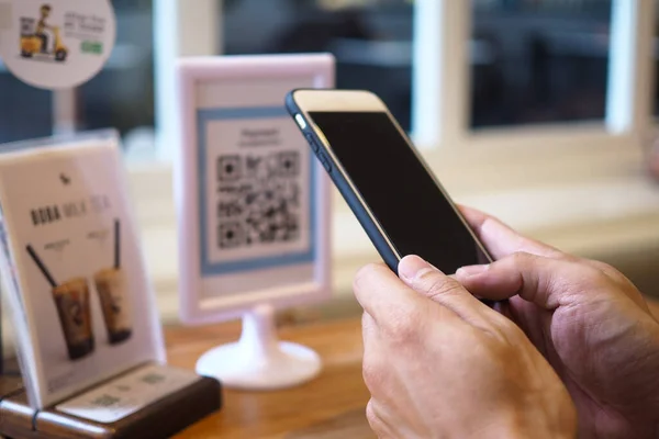 Hands use the phone to scan QR codes to accumulate points in restaurants.