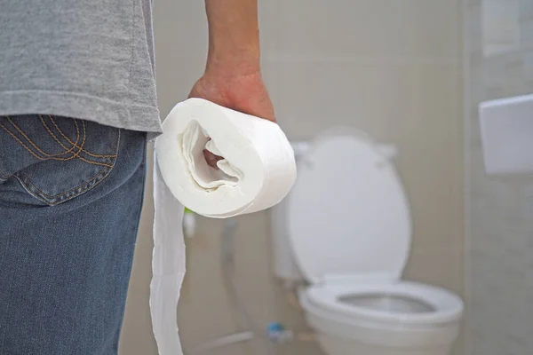 The man holds a tissue paper roll inside the bathroom, going to cum.