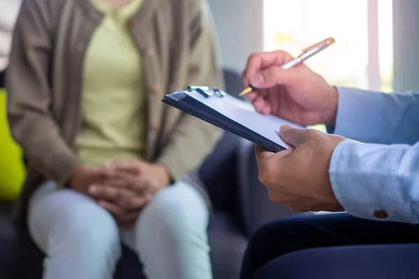 Psikiyatrist hastanın zihinsel semptomlarını kaydediyor. Önerinin yanı sıra danışmanlık ve danışmanlık da yap.