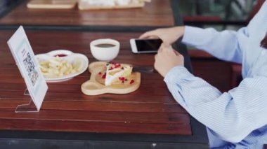 Kadınların elleri yemek menüsünü seçmek için QR kodunu tarıyor. İndirim için tarama yap ya da yiyecek için ödeme yap. Para transferi için telefon kullanma ya da nakit olmadan internet üzerinden para ödeme kavramı..