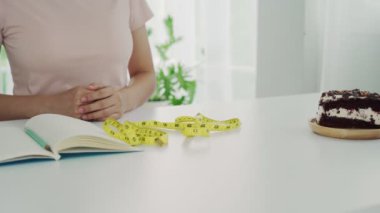 Sağlık hizmetindeki kızlardan biri bir tabak çikolatalı keki itmek için bir el kullandı. Trans Fat içeren yiyecekleri yemeyi reddet.
