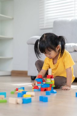 Mutlu Asyalı çocuk oyun oynuyor ve oyuncak bloklarını öğreniyor. Çocuklar evde çok mutlu ve heyecanlı. Çocuk oyun, etkinlik, gelişme ve dikkat eksikliği hiperaktivite bozukluğuyla çok iyi vakit geçiriyor