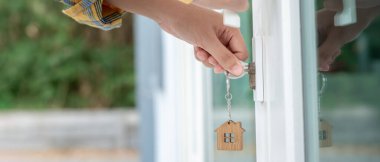 Evin kilidini açmak için ev sahibi anahtarı kapıya takılı. Kira ve satış için ikinci el ev. Sahibi yeni ev, satın al, sat, yenile, yatırım, sahip, mülk