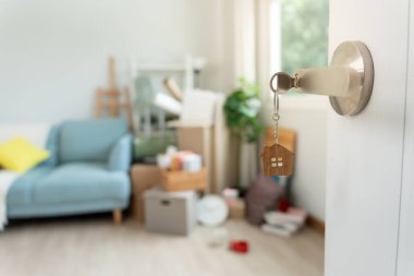 Moving house, relocation. The key was inserted into the door of the new house, inside the room was a cardboard box containing personal belongings and furniture. move in the apartment or condominium