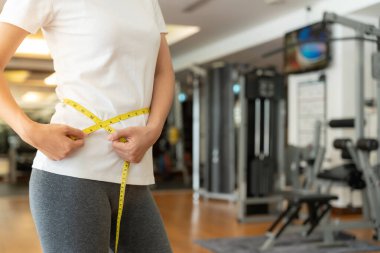 Diyet ve diyet. Güzel, ince kadın vücut ölçüsü fitness için şerit kullanır. Spor elbiseli bir kadın sağlıklı yaşam için kilo verme hedefine, zayıflığa, ince belliye, beslenme uzmanına ulaşır..