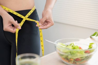 Diyet ve diyet. Güzel, ince kadın vücut ölçüsü. Spor elbiseli bir kadın sağlıklı yaşam için kilo verme hedefine, zayıflığa, ince belliye, beslenme uzmanına ulaşır..