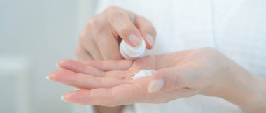 Güzel Asyalı kadın cilt kremini kontrol ediyor. Sağlıklı bir kadın yüzüne krem sürün ve makyaj yapın. Cilt kremi reklamı, kırışıklık önleyici, bebek yüzü, beyazlatma, nemlendirici.