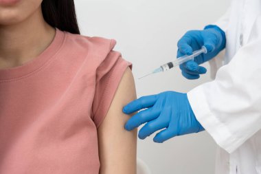 Kadın salgını önlemek için aşı oluyor. Tıp merkezindeki bir hemşire ya da doktordan bir doz bağışıklık aşısı al. Temel aşı, alternatif aşı, risk grubu aşısı.