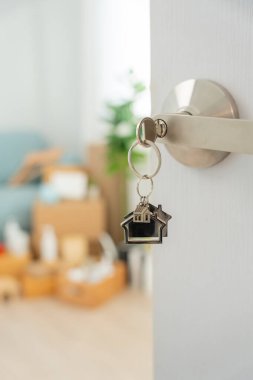 Moving house, relocation. The key was inserted into the door of the new house, inside the room was a cardboard box containing personal belongings and furniture. move in the apartment or condominium