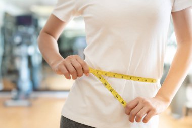 Diyet ve diyet. Güzel, ince kadın vücut ölçüsü fitness için şerit kullanır. Spor elbiseli bir kadın sağlıklı yaşam için kilo verme hedefine, zayıflığa, ince belliye, beslenme uzmanına ulaşır..