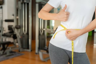 Diyet ve diyet. Güzel, ince kadın vücut ölçüsü fitness için şerit kullanır. Spor elbiseli bir kadın sağlıklı yaşam için kilo verme hedefine, zayıflığa, ince belliye, beslenme uzmanına ulaşır.