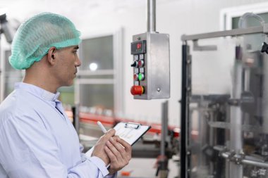 Kalite denetleyicisi, yiyecek veya içecek teknisyeni, müşteriye ürün göndermeden önce durum kontrolü gıda ve içeceklerle ilgili teftiş yapıyor. Üretim lideri makine ve verimliliği yeniden kontrol ediyor.