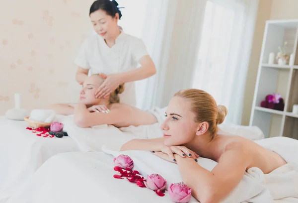 美丽的女人躺在床上享受温泉亚洲按摩 享受奢华的温泉浴和放松 女按摩师正在温泉房里按摩她的脸 — 图库照片
