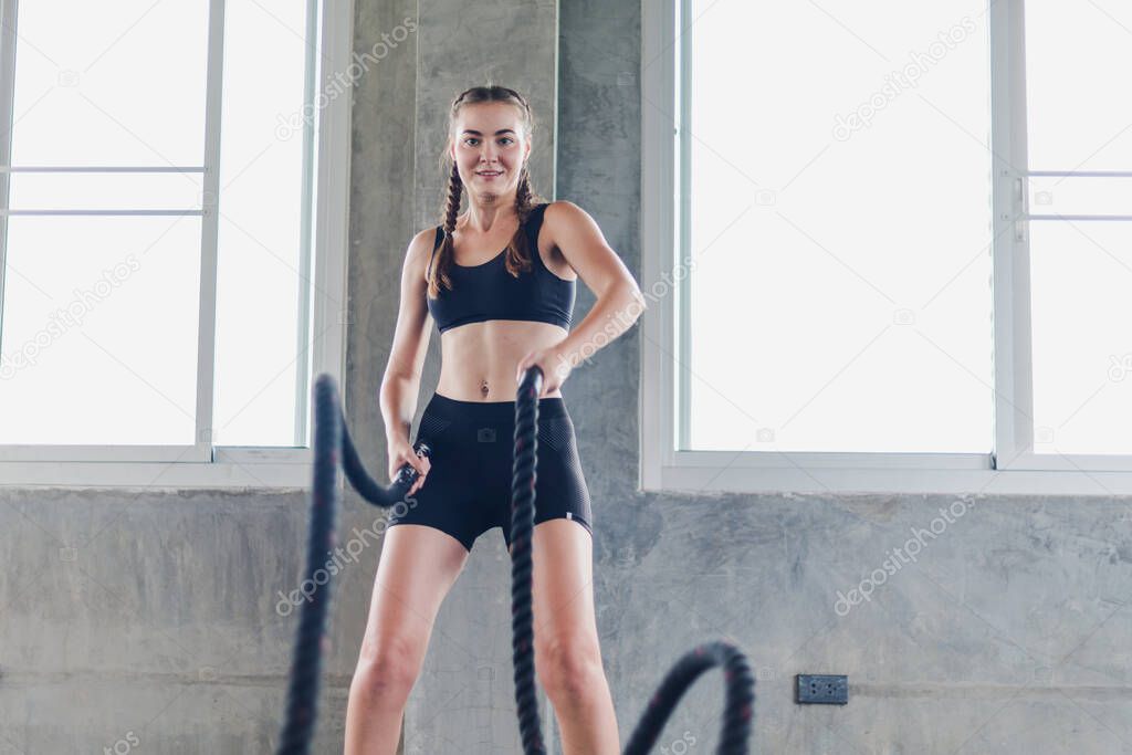 Young female athletes in sportswear exercise in the gym using ropes. Cross fit concept 