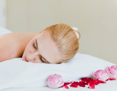Lüks kaplıcalarda spa masajı ve rahatlama için yatakta uzanan güzel bir kadın. O, spa odasında rahat uyudu. Masözden kaplıca masajı beklerken.