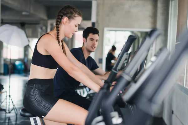 Male and female athletes talk about exercise, cycling in the gym. They wear sportswear to exercise.