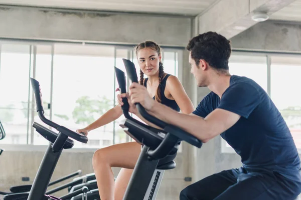 Male and female athletes talk about exercise, cycling in the gym. They wear sportswear to exercise.