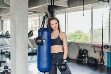 Spor salonunda egzersiz yapmak için kum torbalarını yumruklayan bayan sporcular. Siyah spor giyer. Ve boks eldiveni giy.